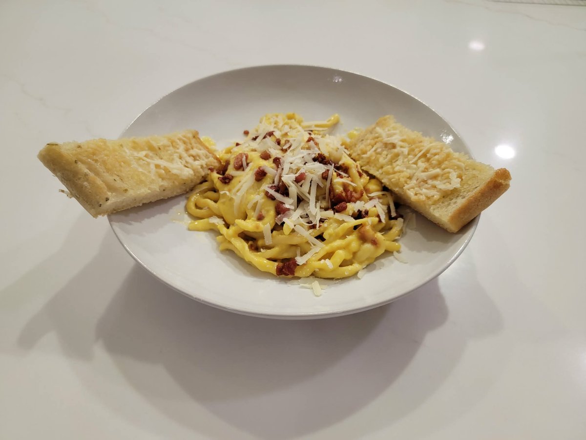 A plate of carbonara with glossy egg and pecorino sauce clinging to every strand of pasta