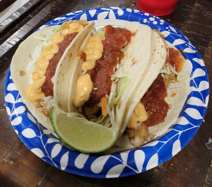 Crispy fish tacos topped with coleslaw and chipotle sauce on a plate