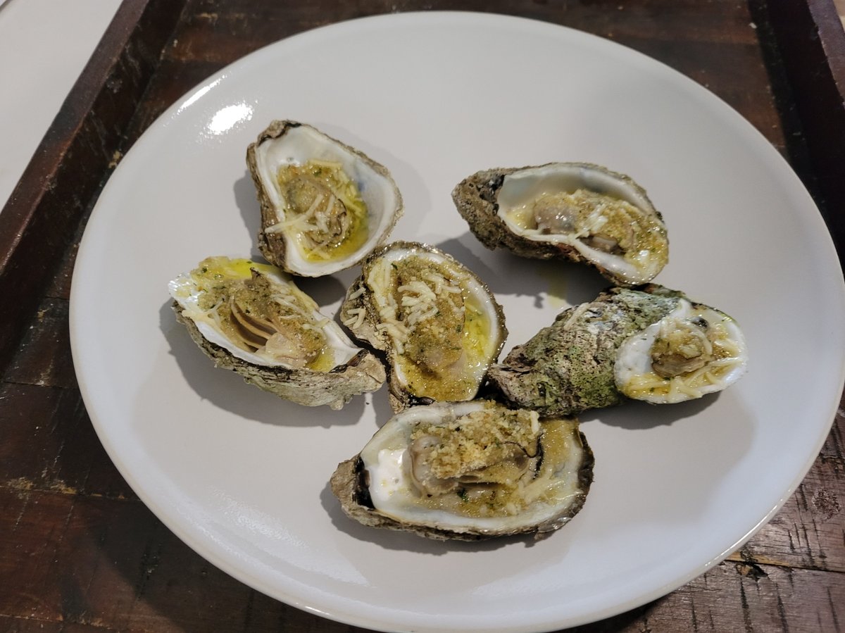 Oysters Rockefeller on a baking sheet, topped with golden bread crumbs and melted parmesan