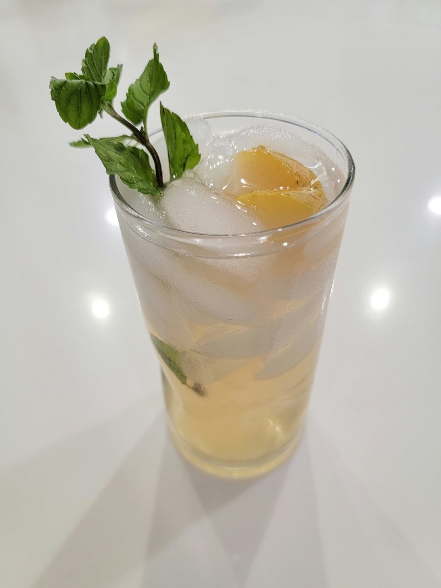 Tall glass of Pear-jito with pear chunks, ice, and a sprig of fresh mint