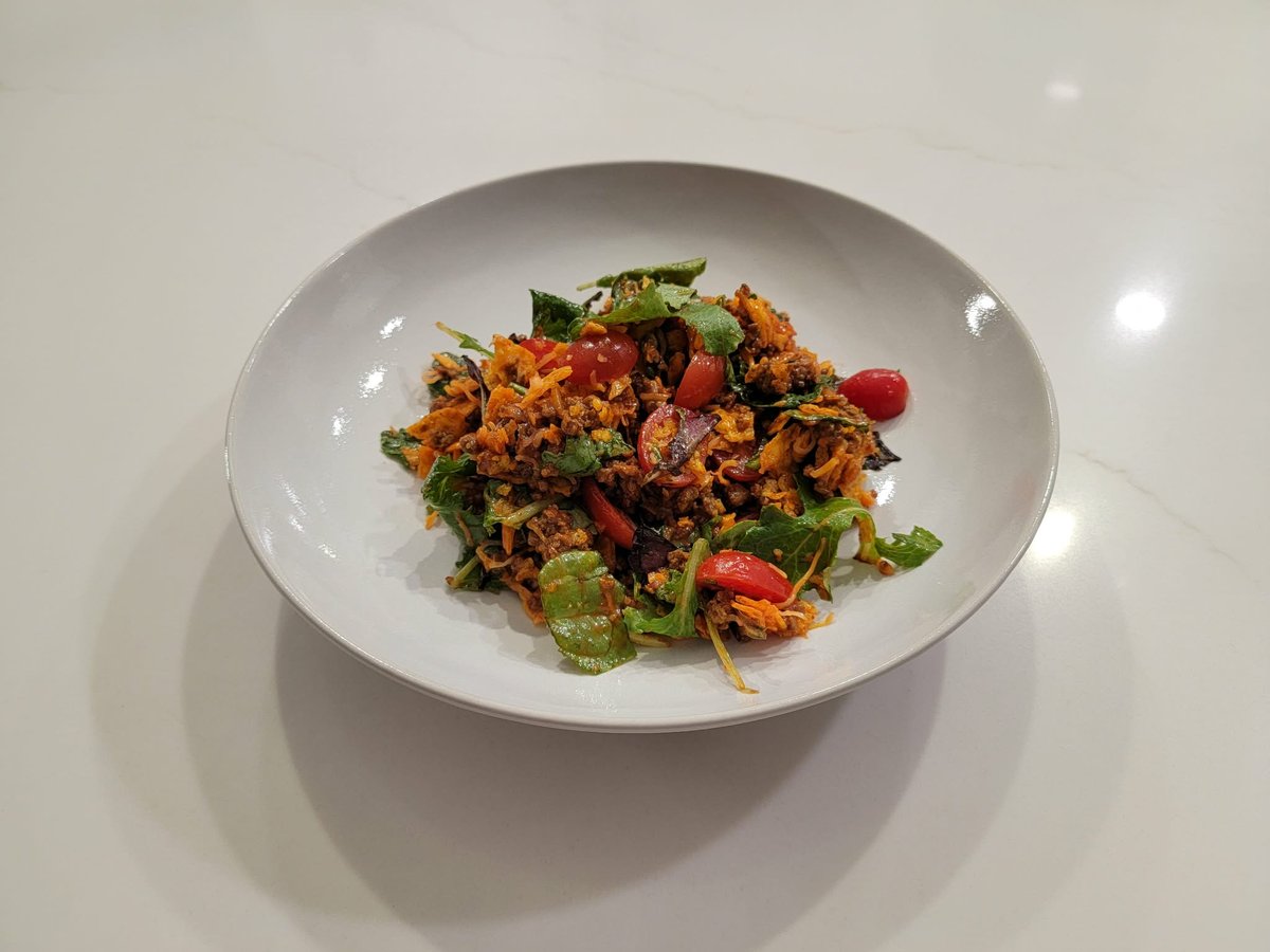 Taco salad with seasoned beef, cheese, crushed Doritos, and Catalina dressing over spring mix