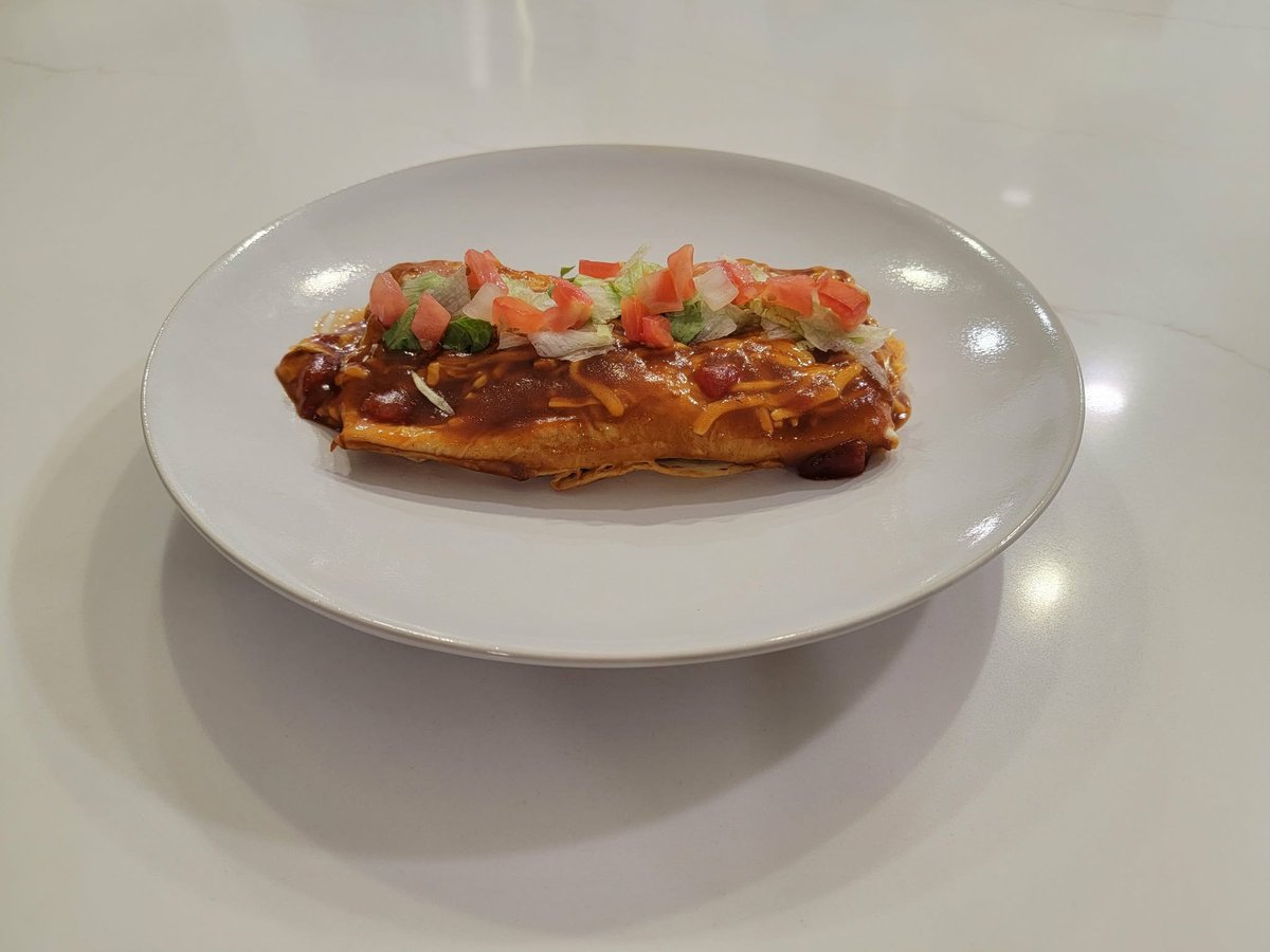 Wet burritos smothered in sauce and melted cheese in a baking dish